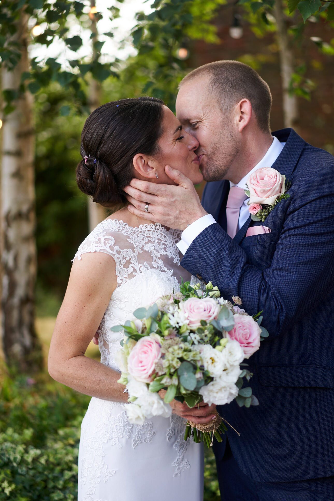 Bride wirh classic low bridal bun kissing her groom on her wedding day at the Walled Garden Beeston Nottingham