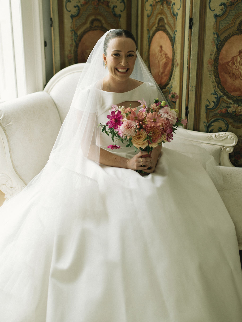 Bride with classic bridal updo and veil holding a pink flower bouquet at Prestwold Hall