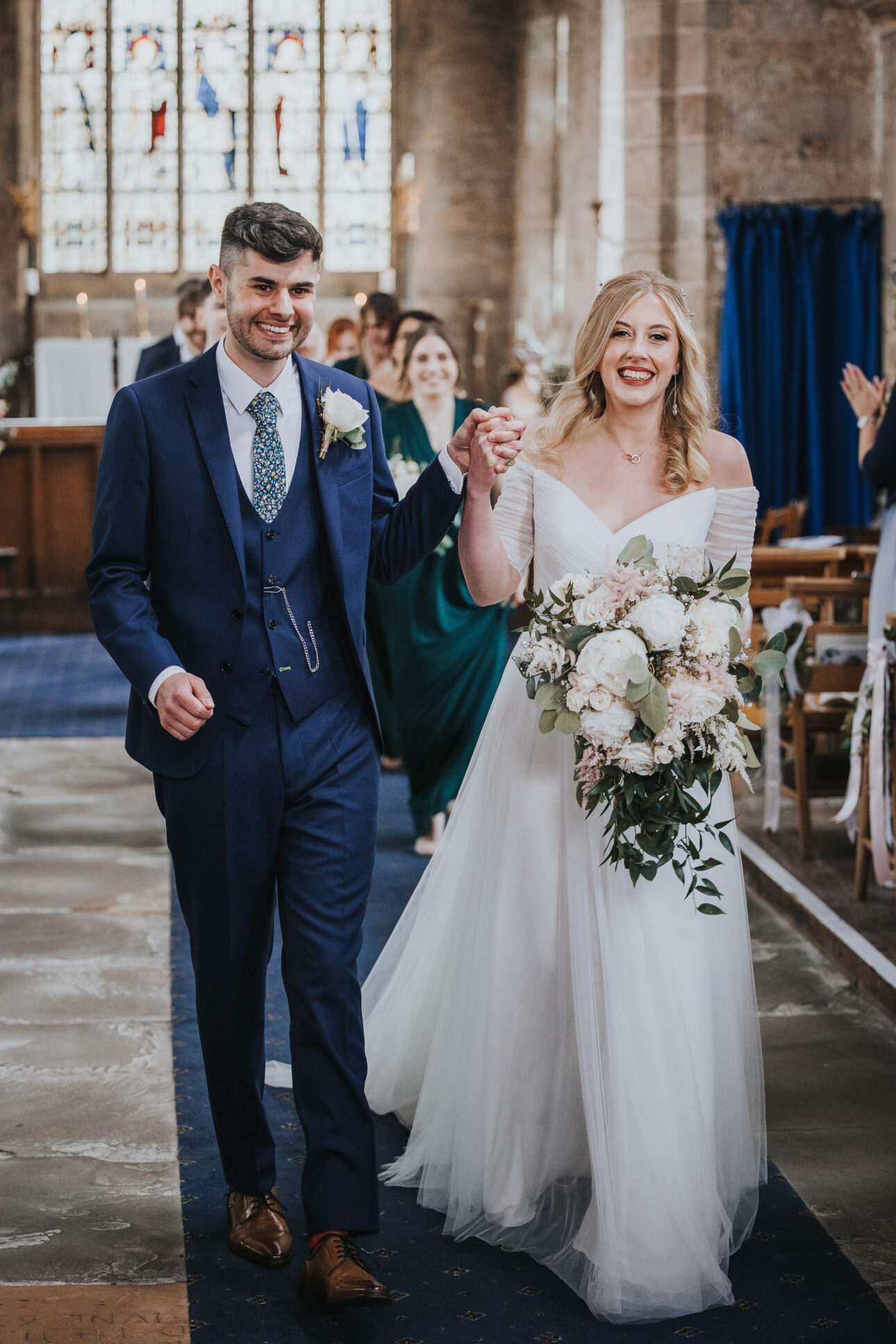 Bride with half up half down soft curls leaving the church with her groom in Nottingham